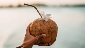 Frau hält Kokosnuss mit Röhrchen in der Hand